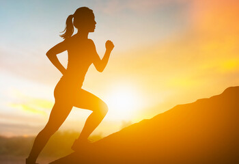 Silhouette of a Woman Running Uphill at Sunset