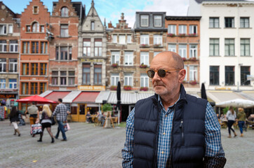 Mature Man Standing Before Historic European Street With Colorful Building Facades