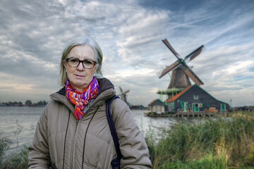 Mature Woman in Scenic Landscape with Traditional Windmills by the Water