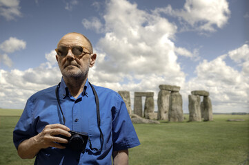 Man Holding Camera in Front of Stonehenge on a Sunny Day