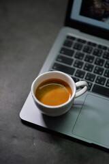 Fresh espresso in a white cup resting on a laptop, symbolizing productivity, modern work, and coffee culture. Perfect for blogs, ads, or creative content.