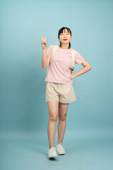 Young Asian woman posing confidently in a casual outfit against a light blue background