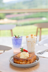 Closeup French toast topped with syrup and a scoop of ice cream with strawberries on top.