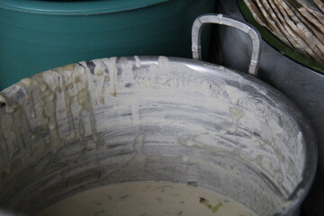 A close-up, textured shot of a stainless steel bowl with remnants of white dough or batter. The...