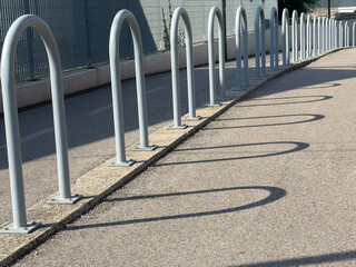 Urban sidewalk with metal bike racks casting curved shadows
