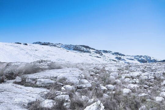 Fototapeta Flat design illustration is showing snow-covered rocky plateau and hillside under vivid blue sky