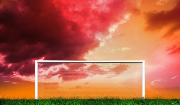 Fototapeta Football goal under orange and red cloudy sky