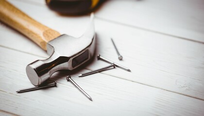 Flat design claw hammer and scattered nails are resting on painted white wooden plank surface