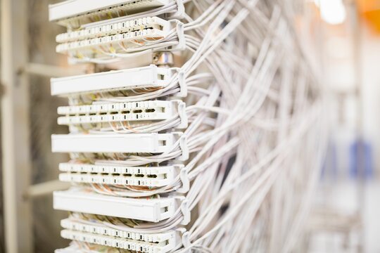 Network patch panel is being shown close-up in 3D render with Ethernet cables under warm light