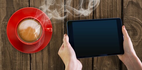 Flat design scene showing hands holding tablet over wooden plank table with steaming coffee cup