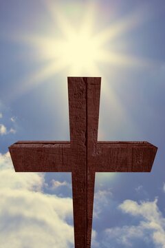 Fototapeta Wooden cross is standing tall in flat design, with grain texture, glowing sun rays and clouds