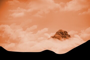 Rocky mountain peak is emerging through orange-tinted cloud layers over abstract black silhouette
