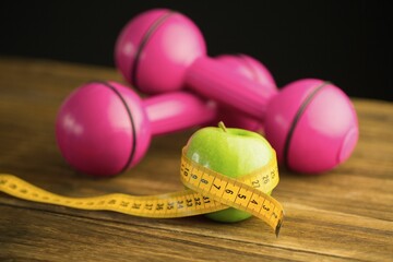 Pink dumbbells with green apple and measuring tape