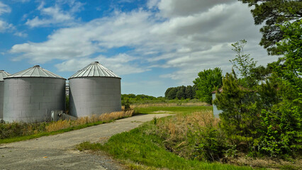 Rural scene featuring large grain silos under a vibrant blue sky, reflecting agricultural industry....