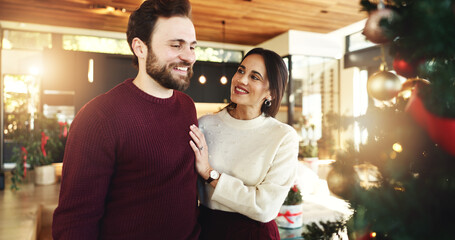 Christmas, couple and smile for tree, home and romance in festive season, decoration or celebration. Happy, man and bonding with woman on holiday, December or love on weekend in house or relationship