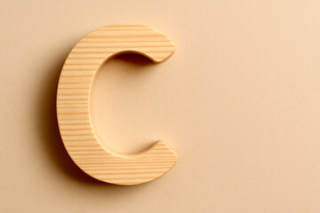3D Capital Wooden Letter C in Curved Modern Style Made of Light Pine Wood – Smooth Finish on Beige Background with Empty Space for Text, Design, or Mockup Use