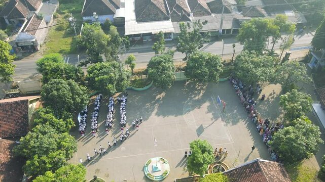 Aerial view A large group of junior high school students in uniform stand in formation during morning assembly