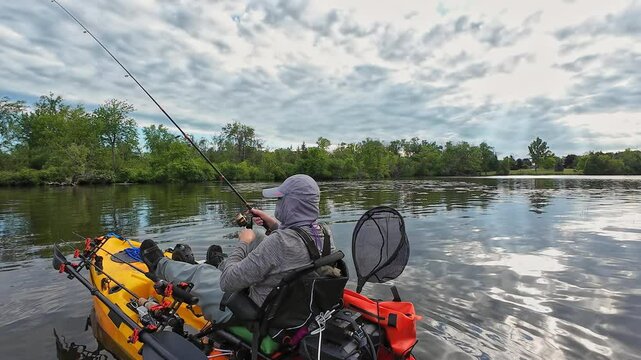 Kayak paddle at lake or pond during fishing game sport action. Fisherman with fishing gear on pedal kayak paddles and casting. Leisure active lifestyle recreation and sport activity.