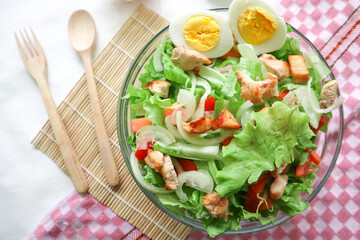 A cesar salad bowl filled with lettuce, tomatoes, egg and chicken. The salad is served in a clear glass bowl