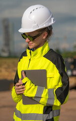 Obraz premium Vertical female refinery engineer holding tablet working in oil field