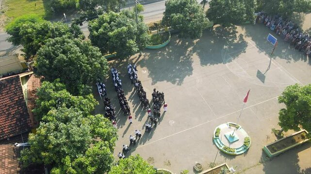 Aerial view A large group of junior high school students in uniform stand in formation during morning assembly
