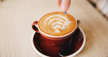 Table, hands and sugar in cappuccino at restaurant for caffeine, prepare beverage and warm drink....