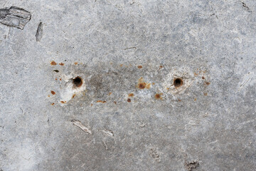 Two holes on a concrete wall with rusty marks