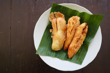 fried bananas or pisang goreng served on a plate with banana leaf. The plate is on a wooden table
