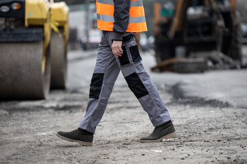 Naklejka premium Construction worker walking on site during daytime while wearing safety gear for traffic control