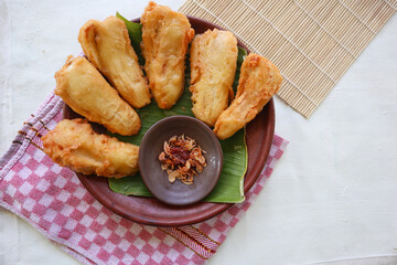 fried bananas or pisang goreng served on a plate with banana leaf. The plate is on a wooden table