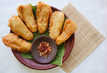 fried bananas or pisang goreng served on a plate with banana leaf. The plate is on a wooden table
