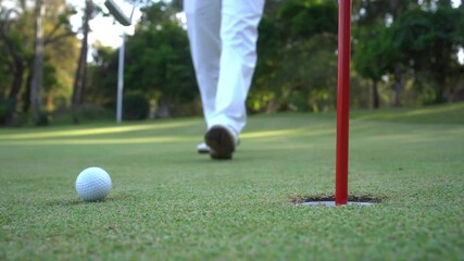 Golfer putting ball on the green golf, lens flare on sun set evening time. Golfer hitting golf ball. Sport holiday lifestyle Concept - Powered by Adobe