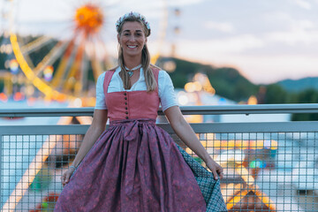 At golden hour, a woman in traditional Bavarian dress enjoys the sunset before the start of a folk...