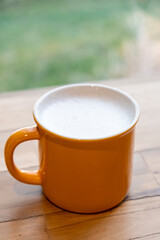 Milk in a yellow cup, on the wooden table