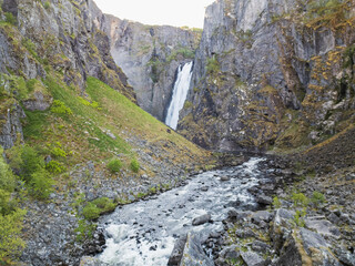 The majestic Vøringsfossen waterfall, cascading into the deep and rocky Måbødalen canyon, Norway. A turbulent mountain river flows through the valley amidst the rugged Scandinavian landscape.