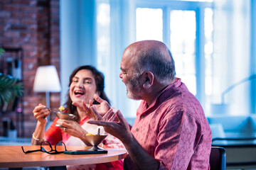 Old Indian couple eating ice cream sitting together and enjoying sweet moment indoors
