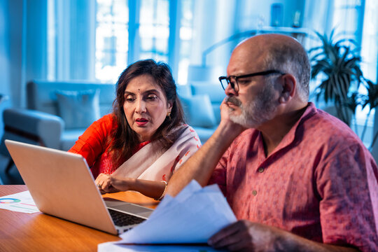 Elderly couple using laptop to manage pension planning, bills, and household finance at home