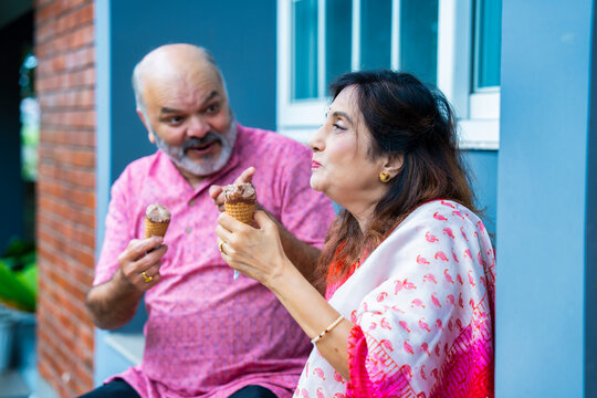 Asian elderly couple happily enjoying ice cream together outside on a warm sunny day