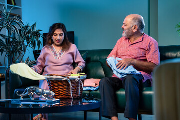 Elderly Indian couple folding laundry together and chatting happily during home routine