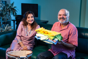 Elderly Indian couple folding laundry together and chatting happily during home routine