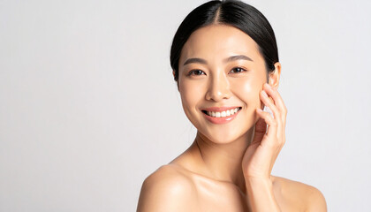 the image features a person with smooth skin, smiling brightly against a soft, light background. the individual's dark hair is pulled back, highlighting their face