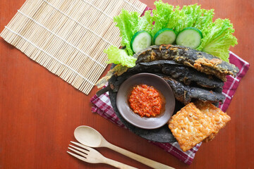 Pecel lele or pecak lele or penyetan consisting of catfish, tempeh, tomato sambal, catfish fried then served fresh vegetables, cucumbers, cabbage