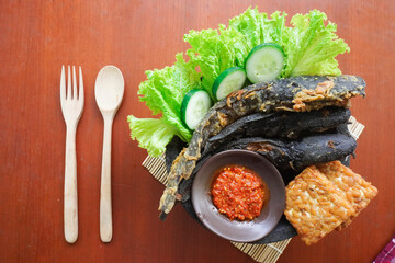 Pecel lele or pecak lele or penyetan consisting of catfish, tempeh, tomato sambal, catfish fried then served fresh vegetables, cucumbers, cabbage