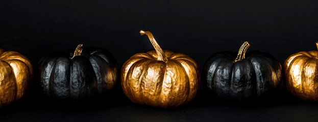 Halloween celebration. Black and gold pumpkins on a black background. Decor for the Day of the Dead...