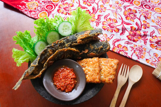 Pecel lele or pecak lele or penyetan consisting of catfish, tempeh, tomato sambal, catfish fried then served fresh vegetables, cucumbers, cabbage