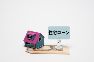 一万円札と住宅模型で住宅ローンのイメージ