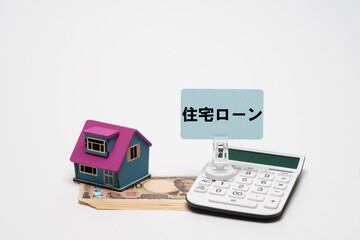 一万円札と住宅模型と電卓で住宅ローンのイメージ