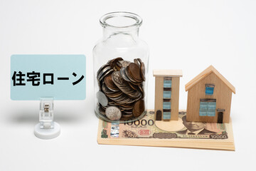 一万円札とコインと家の模型で住宅ローンのイメージ