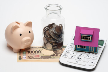 豚の貯金箱と電卓と一万円札と小銭で住宅ローンのイメージ