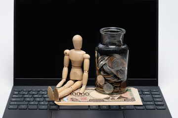 ノートパソコンと瓶に入ったコインと一万円札とデッサン人形